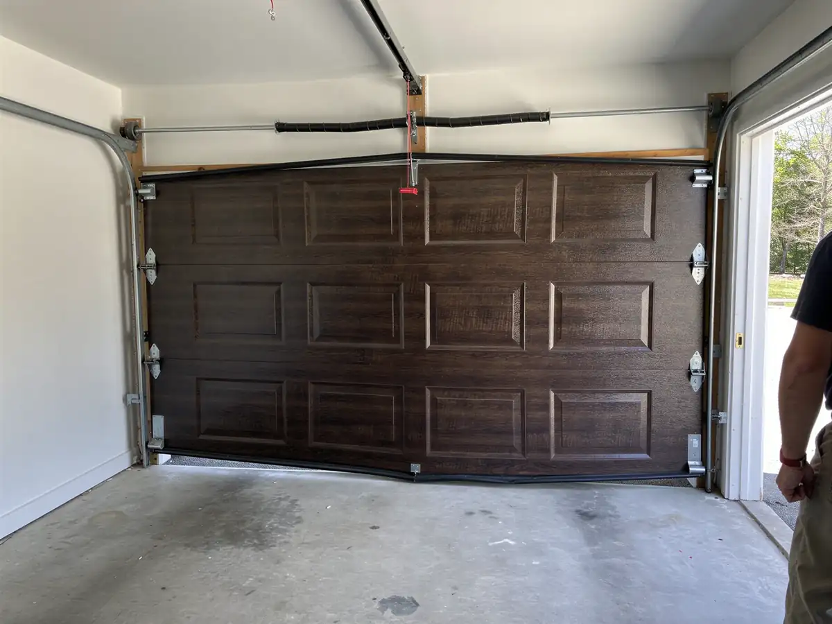 A dark brown garage door is off its tracks and partially open.